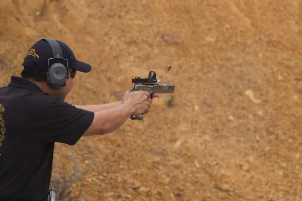 Practical pistol competitor, shell ejecting mid-shot.